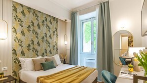 Ein Hotelzimmer mit Bett, Schreibtisch mit Stuhl, Spiegel und einem Fenster mit Vorhängen.
