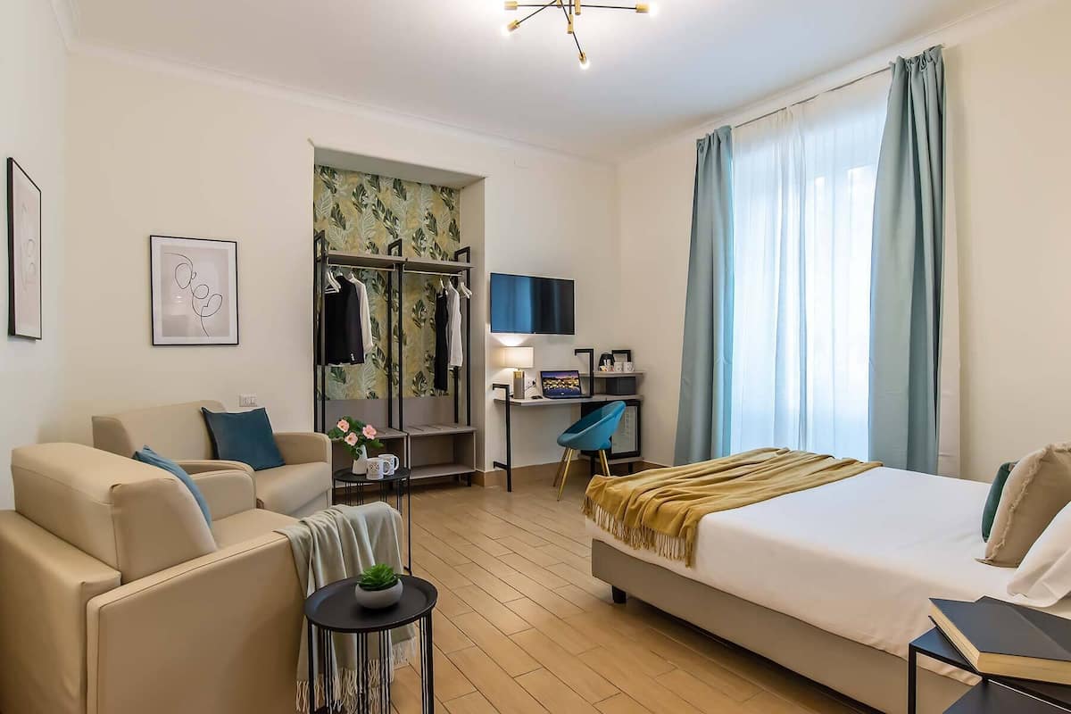 Une chambre d’hôtel comprenant un lit, un canapé, un bureau avec un ordinateur, une télévision et une armoire.