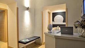 Ein Empfangsschalter mit einem Laptop, einer Vase mit Trockenblumen und einem gerahmten Bild eines Gebäudes.