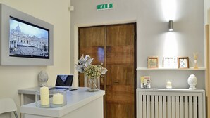 Ein Empfangstresen mit einem Laptop, zwei Kerzen, einer Blumenvase und einem gerahmten Bild.