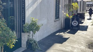 Eine schmale Straße mit einem Gebäude, auf dem „DAFNE GARDEN“ steht, und einem Schild für einen Coffeeshop.