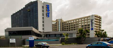 Un moderno edificio de hotel con un llamativo letrero que dice 'Park Inn', que presenta un diseño contemporáneo con grandes ventanales y un techo plano.