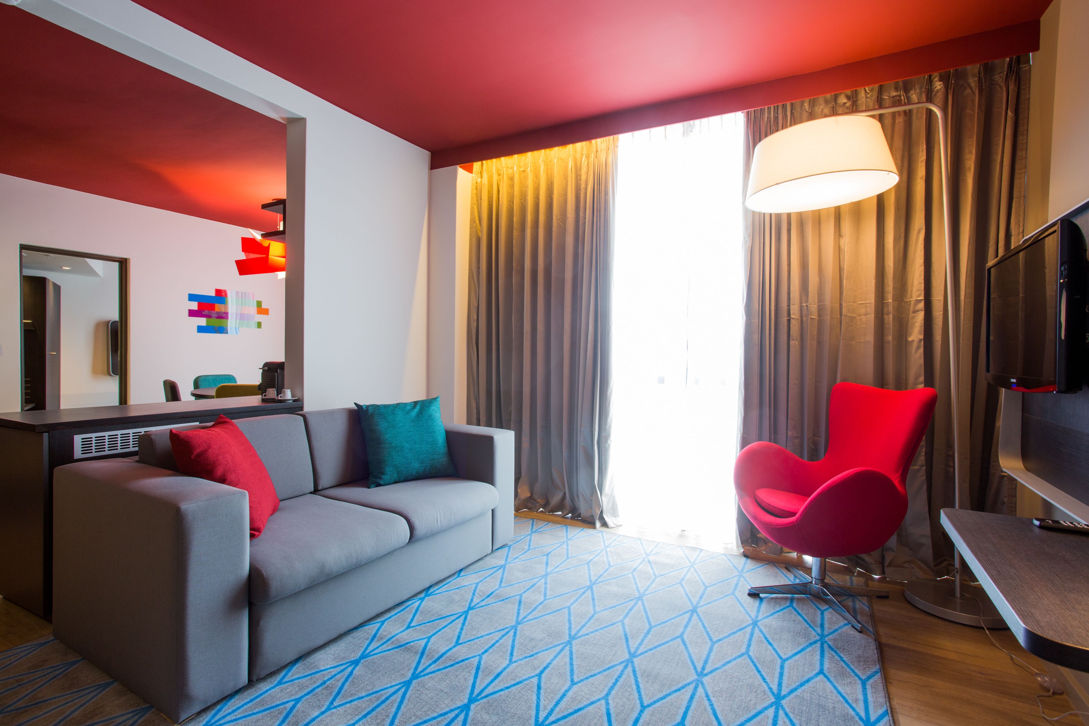 Una sala de estar moderna con un sofá gris, un sillón rojo y un televisor.