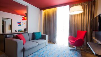 Una sala de estar moderna con un sofá gris, un sillón rojo y un televisor.