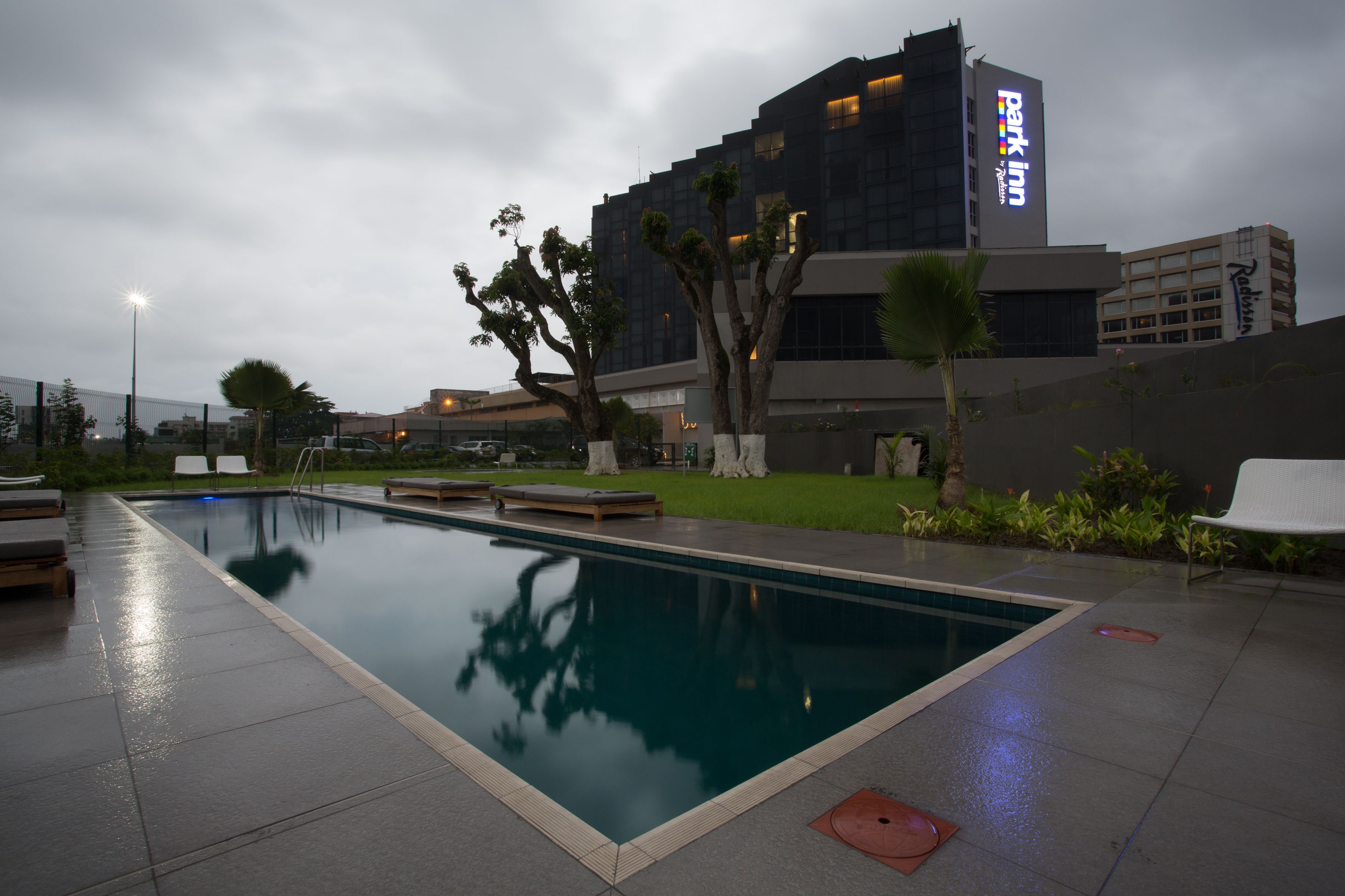 A swimming pool with lounge chairs and a building with a sign that reads "Park Inn."