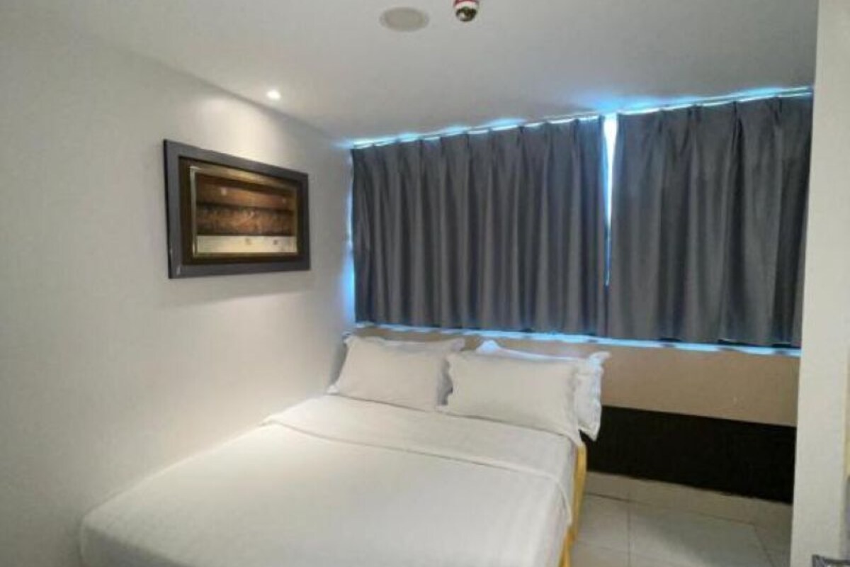 Quarto com cama, quadro emoldurado na parede e janela com cortinas.