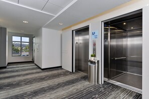 A modern elevator with a digital display, a trash bin, and a sign indicating the elevator's direction.
