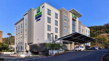 Um hotel de vários andares com design moderno, com entrada coberta e vários espaços de estacionamento.