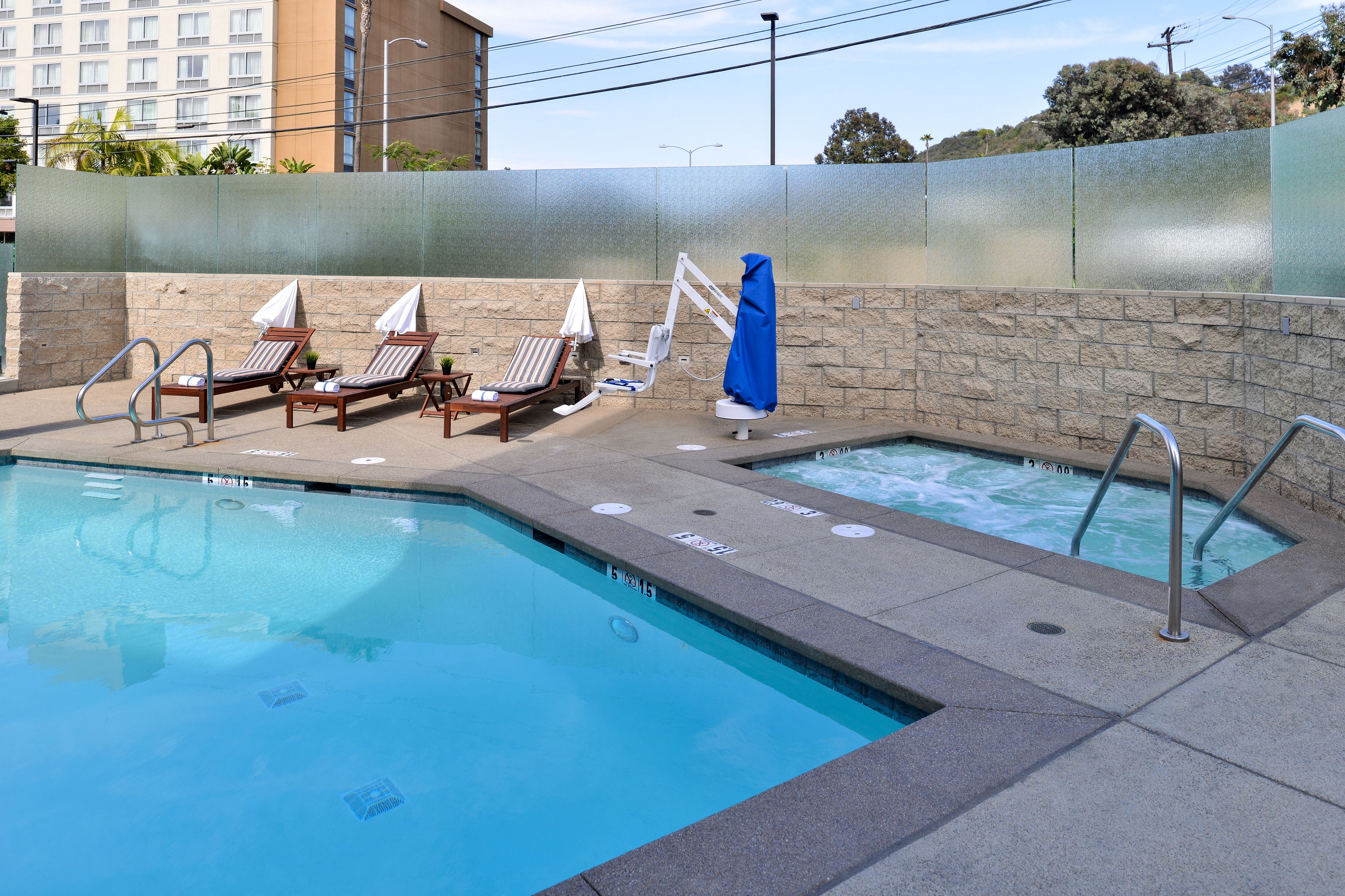 A swimming pool with lounge chairs and a hot tub.