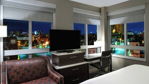 Une chambre d’hôtel dotée d’une grande fenêtre, d’un téléviseur à écran plat, d’un bureau, d’une chaise et d’un canapé.