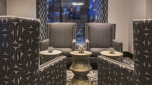 A lounge area with patterned armchairs, a central round table, and a chandelier. - Fairfield Inn & Suites Boston Cambridge (Cambridge)