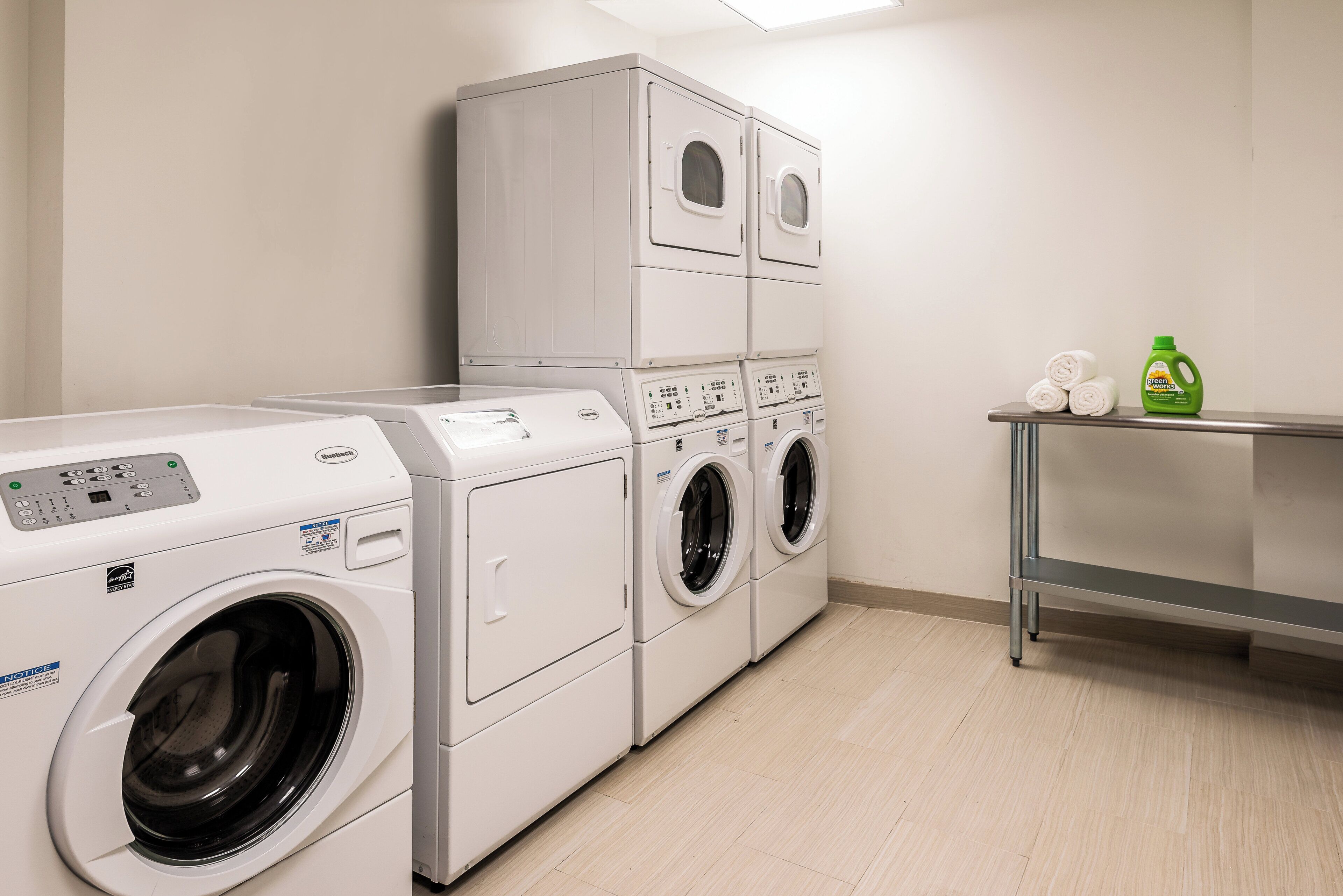 A laundry room with stacked washing machines and a table with cleaning supplies.