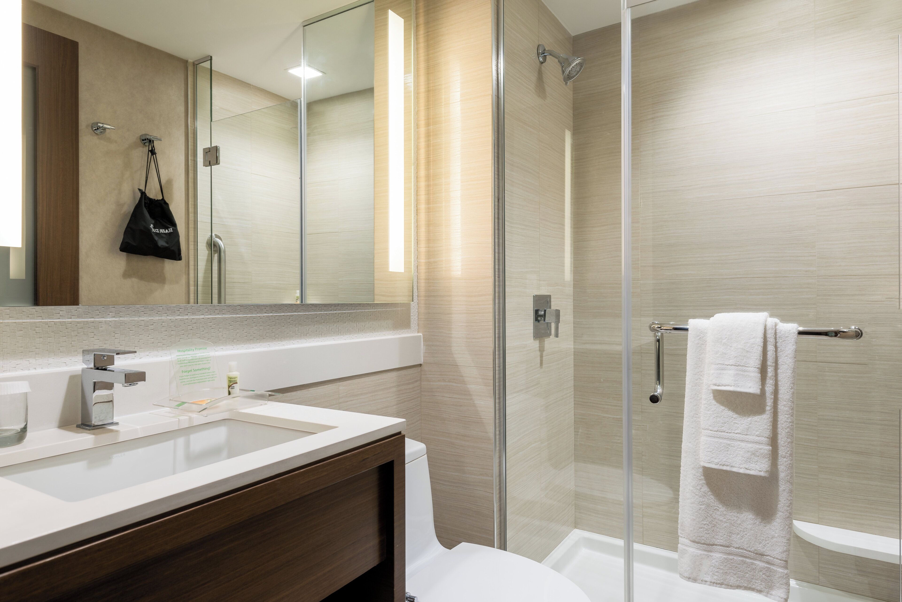 A modern bathroom with a glass shower enclosure, a white sink, and a mirror.