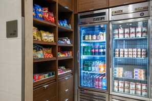 Máquina expendedora llena de refrigerios y bebidas, como papas fritas, refrescos y agua embotellada.