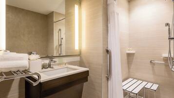 A modern bathroom with a shower, a sink, a mirror, and a towel rack.