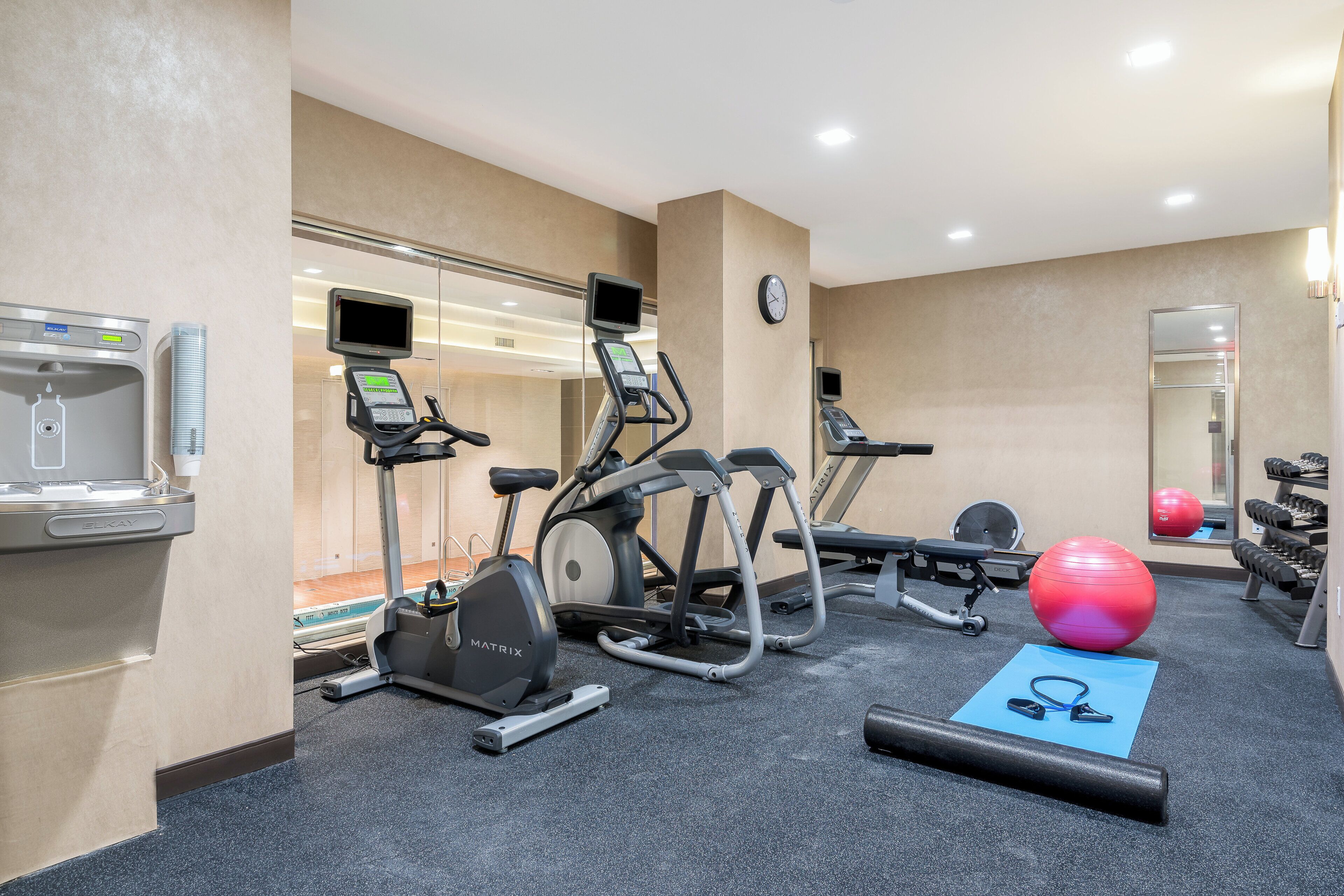 Un gimnasio con cintas de correr, elípticas, una máquina de remo, pesas libres y pelotas de ejercicio.