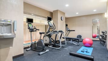 Un gimnasio con cintas de correr, elípticas, una máquina de remo, pesas libres y pelotas de ejercicio.