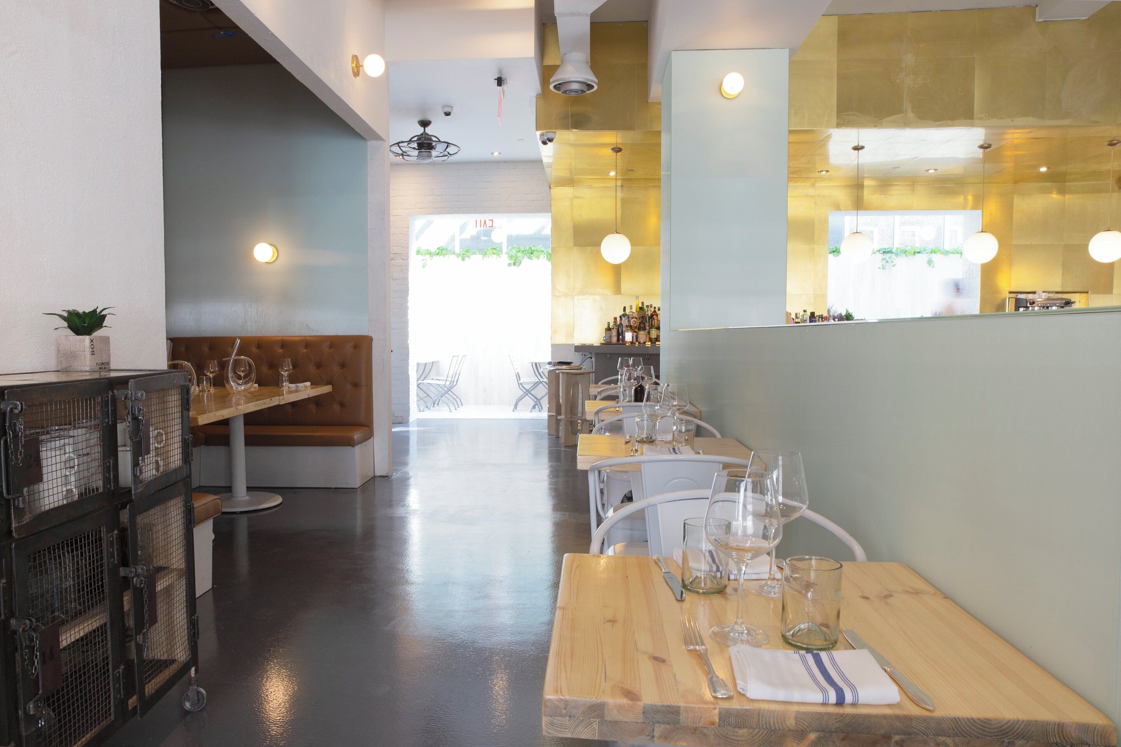 Een restaurantinterieur met houten tafels, witte stoelen en een bar.