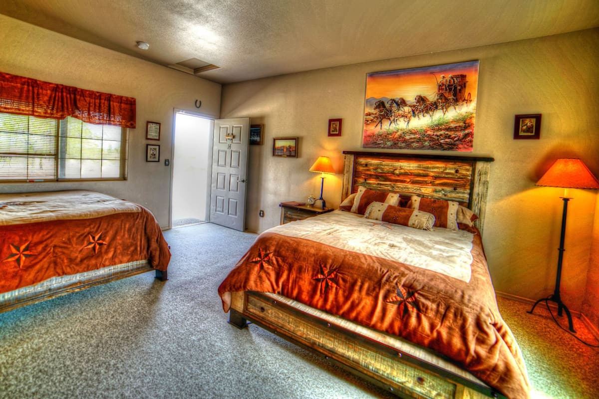 A hotel room with two beds, a large painting on the wall, and a door leading to another room.
