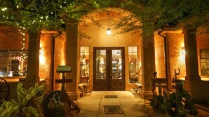 A warmly lit building entrance with a central door, flanked by columns and a canopy of greenery. - Stagecoach Trails Guest Ranch (Yucca)