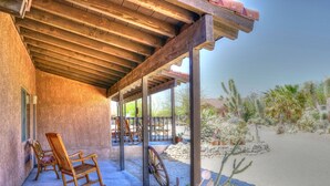 A covered patio with wooden rocking chairs and a cactus garden. - Stagecoach Trails Guest Ranch (Yucca)