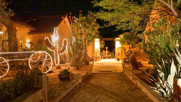 A nighttime garden pathway leading to a building with a tiled roof. - Stagecoach Trails Guest Ranch (Yucca)