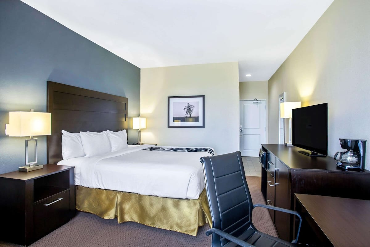 A hotel room with a large bed, bedside lamps, a desk with a television, and a coffee maker.