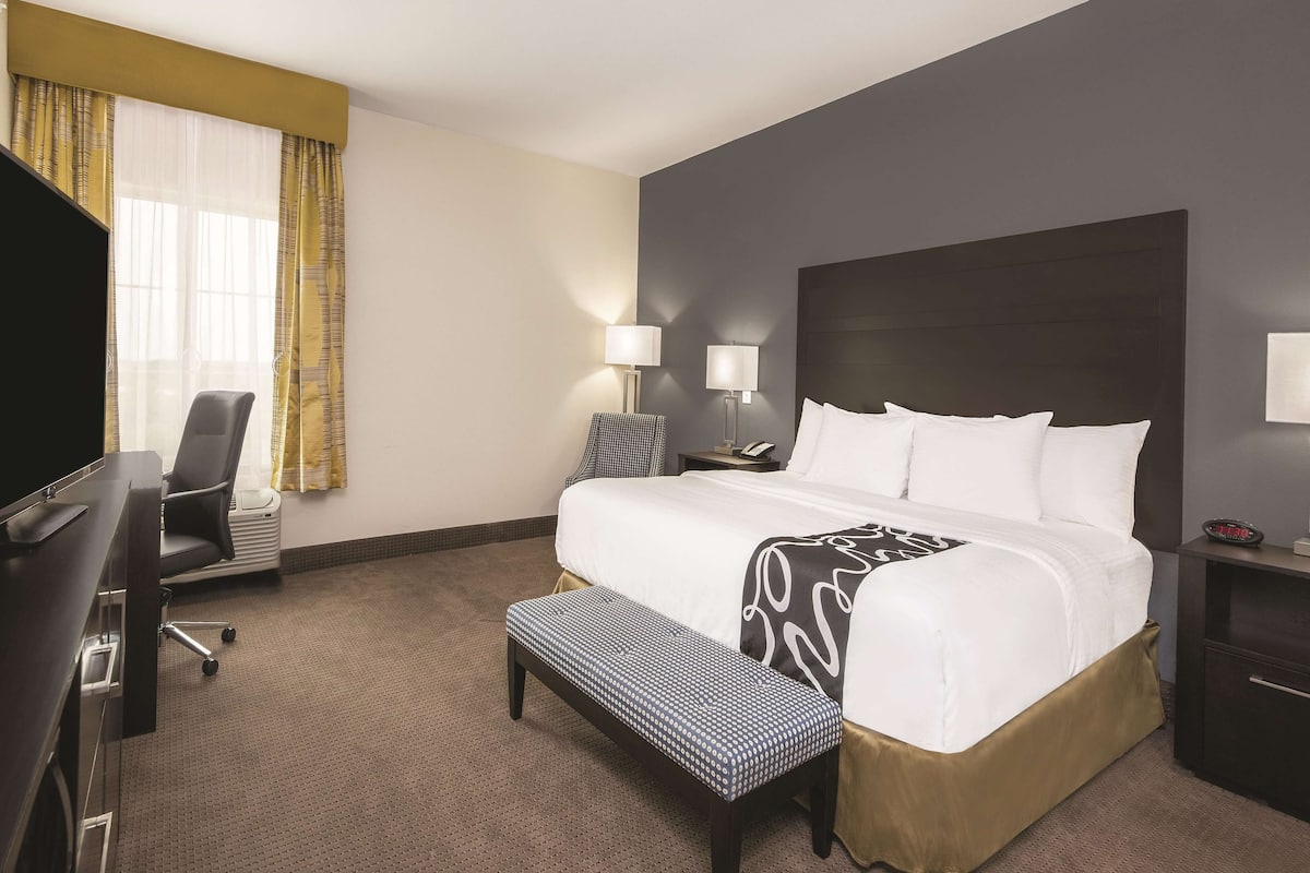 A hotel room with a large bed, bedside lamps, a desk, and a chair.