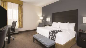 A hotel room with a large bed, bedside lamps, a desk, and a chair.