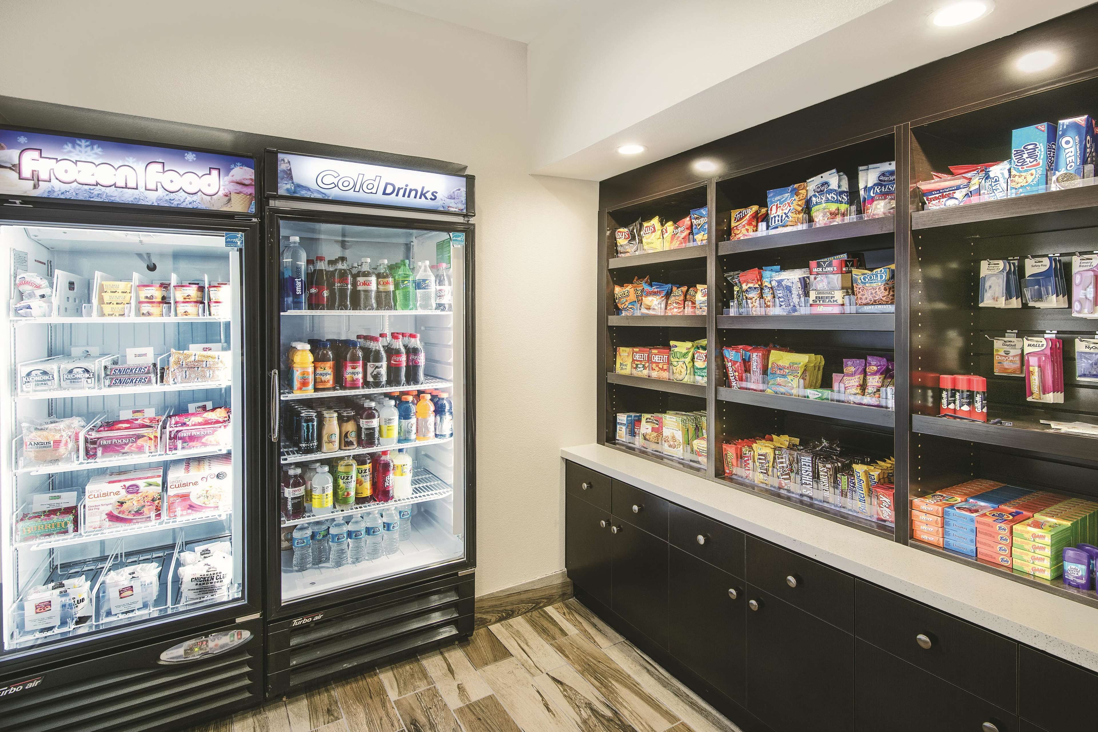 A refrigerated display case with frozen food and cold drinks, and adjacent shelves stocked with snacks and packaged goods.