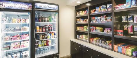 A refrigerated display case with frozen food and cold drinks, and adjacent shelves stocked with snacks and packaged goods.