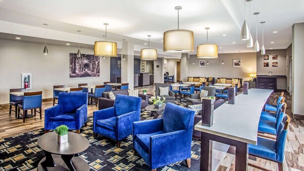 Um hall de hotel com poltronas azuis, área de bar e espaço para refeições.