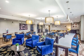 Una hall d'albergo con poltrone blu, un'area bar e una sala da pranzo.
