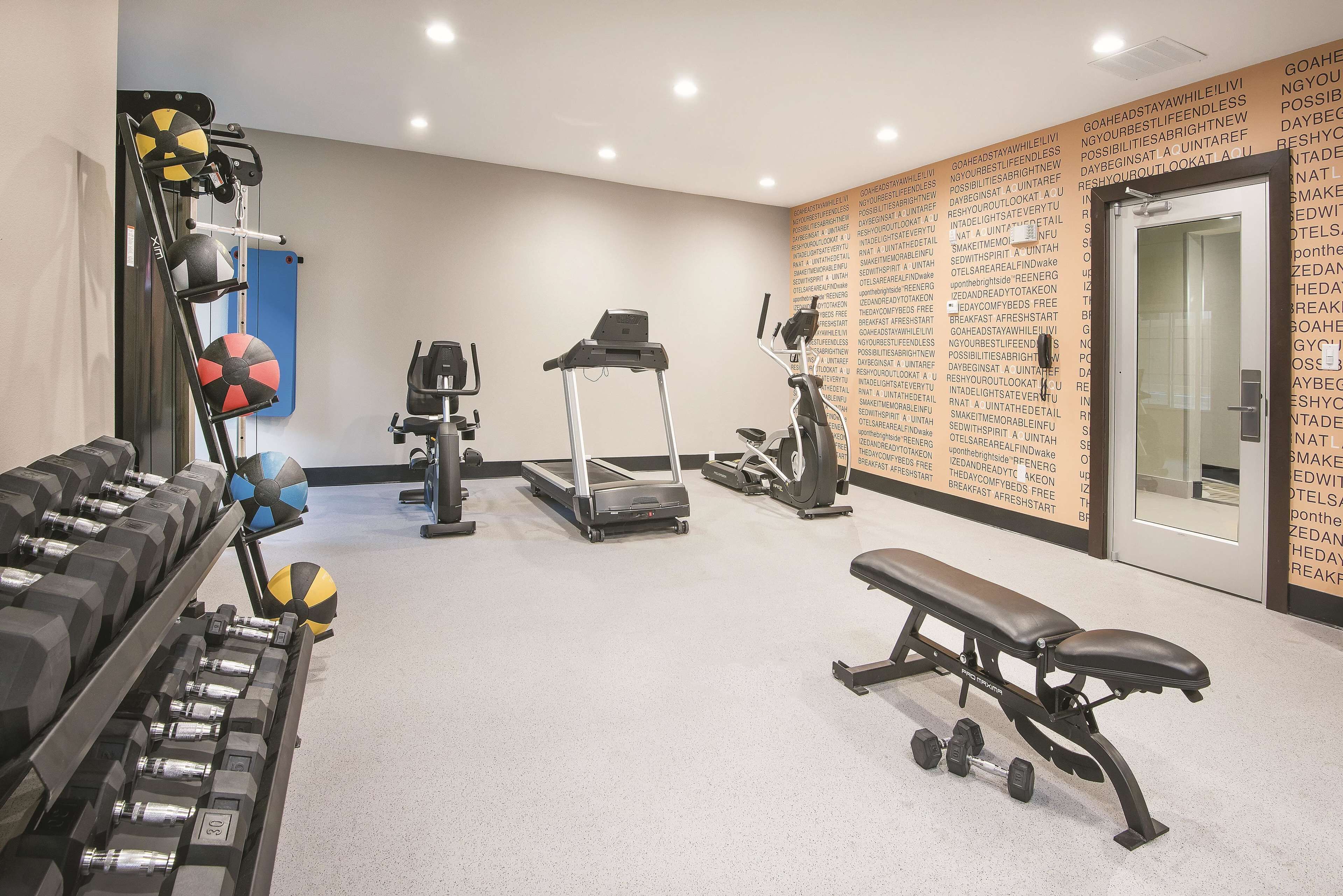A gym with treadmills, elliptical machines, and free weights.