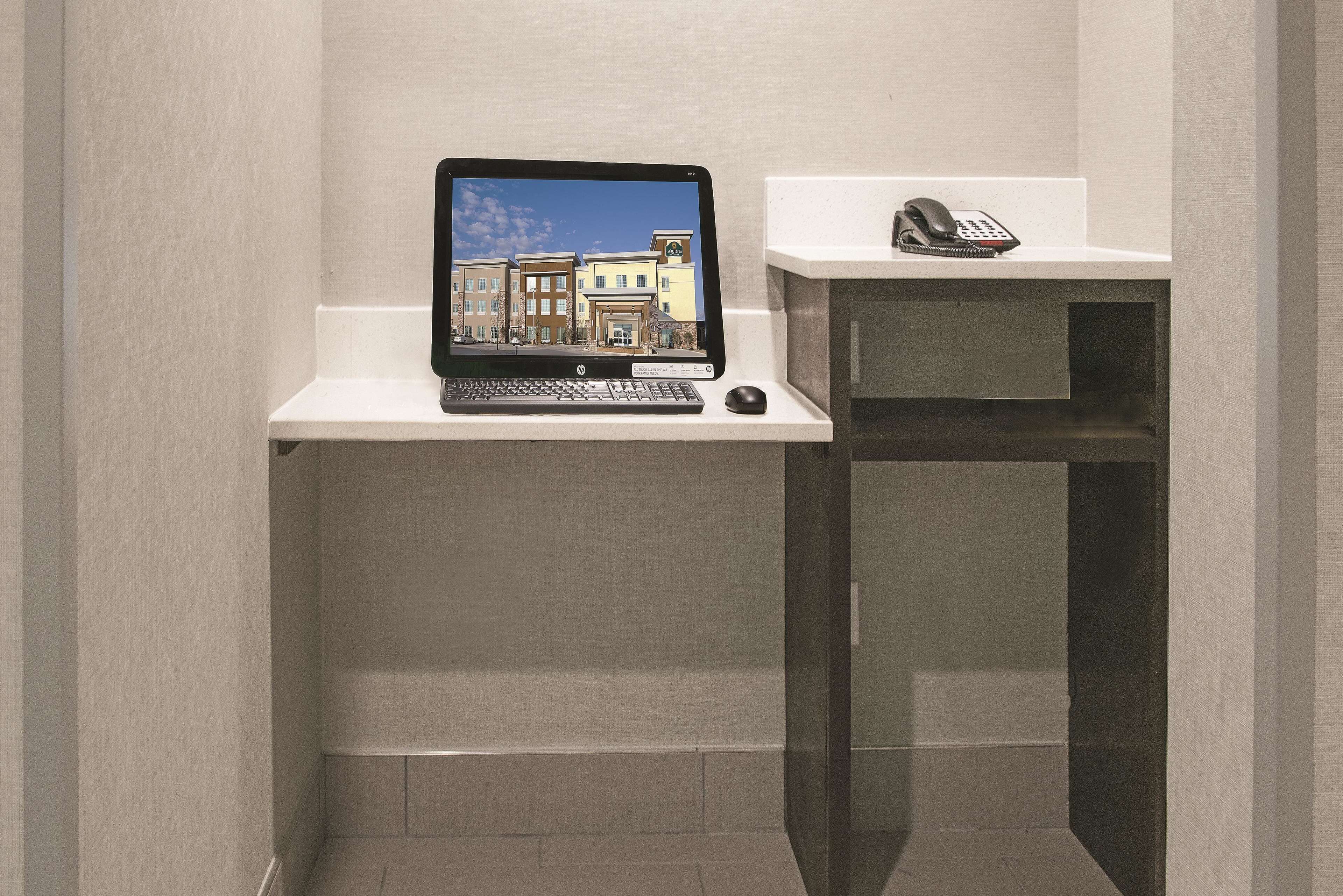 A laptop on a white shelf with a telephone beside it.
