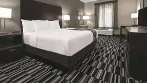 A hotel room with a large bed, two bedside tables with lamps, a desk with a chair, a large window with curtains, and a wall-mounted TV. - La Quinta Inn & Suites by Wyndham Fort Worth West - I-30 (Fort Worth)