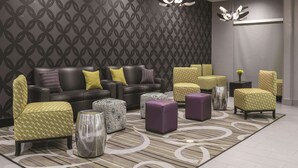 A modern lounge area with a patterned wall, leather sofas, patterned ottomans, and contemporary lighting fixtures. - La Quinta Inn & Suites by Wyndham Fort Worth West - I-30 (Fort Worth)