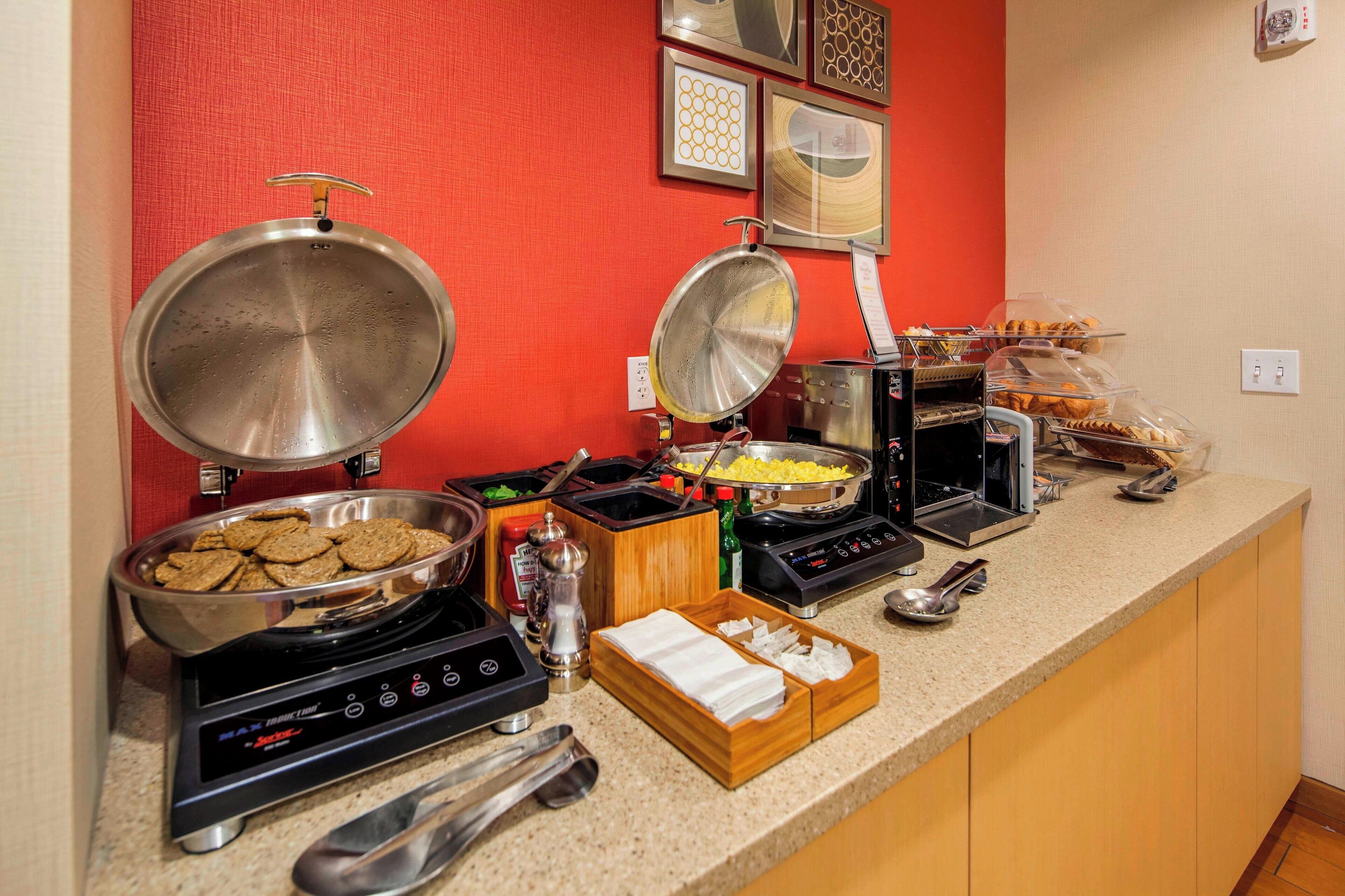 A buffet setup with various food items and cooking appliances.