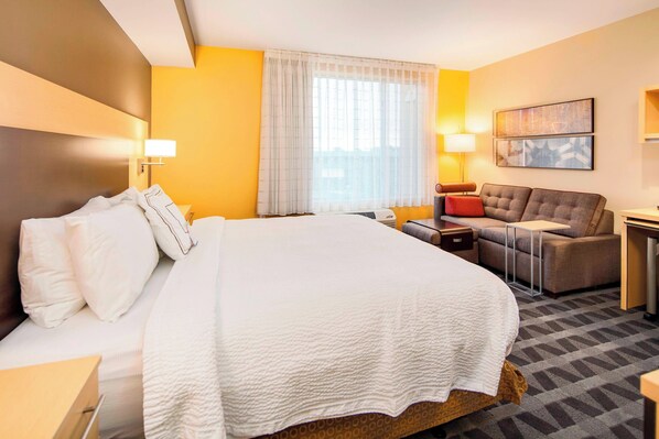 Une chambre d’hôtel avec un grand lit, un canapé, un bureau et une fenêtre avec des rideaux.