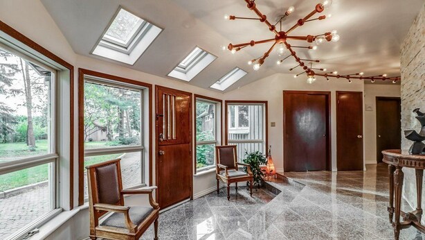 A spacious hallway with skylights, a chandelier, and a view of the outdoors.