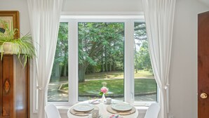A dining table set for four with plates, cutlery, and a vase with flowers.