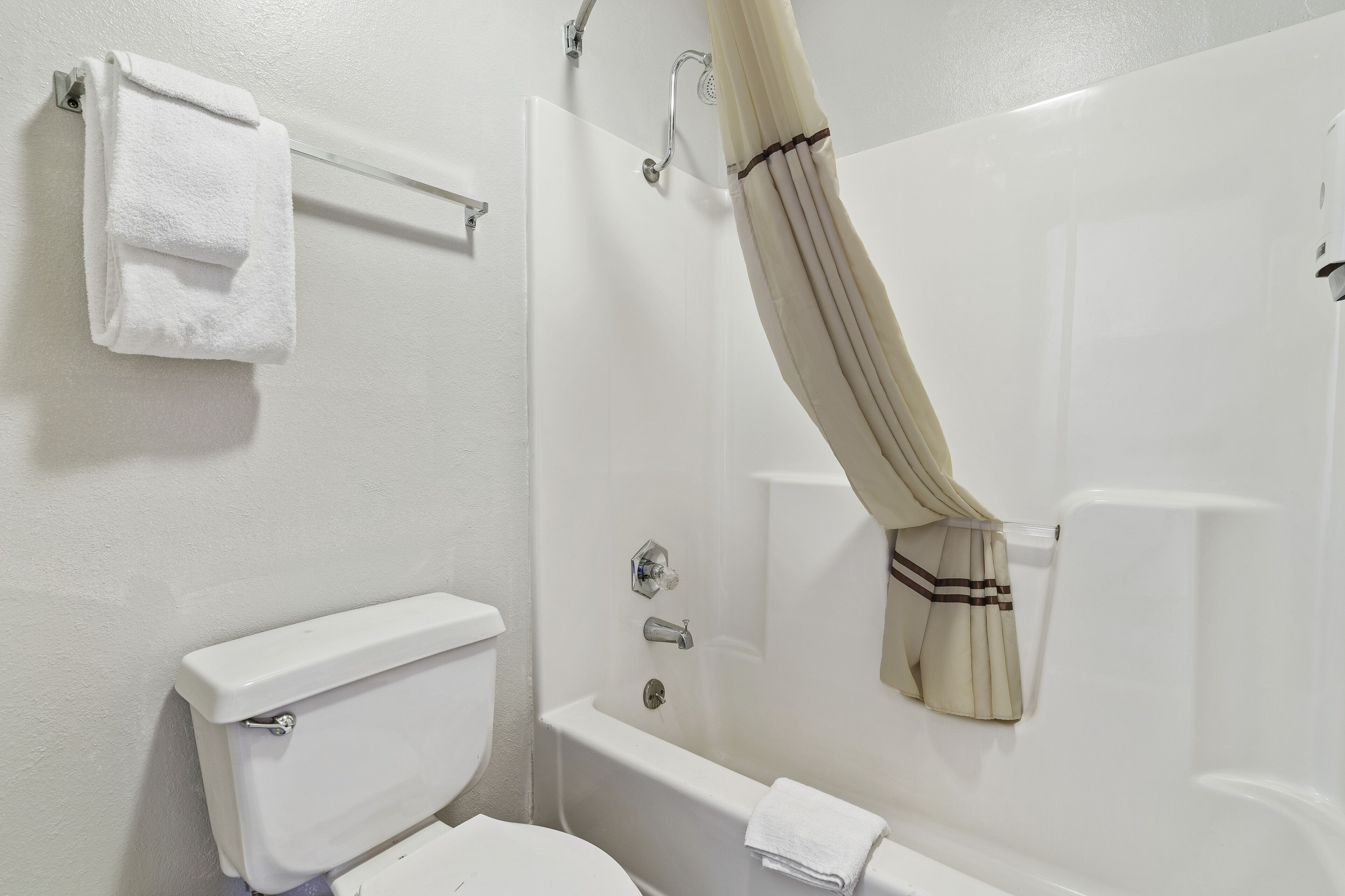 A bathroom with a toilet, a bathtub, and a shower curtain.