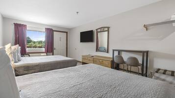 Une chambre d’hôtel avec deux lits, une télévision, une commode en bois et une fenêtre avec des rideaux.
