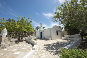 A courtyard with a small building, stone pathway, and trees.