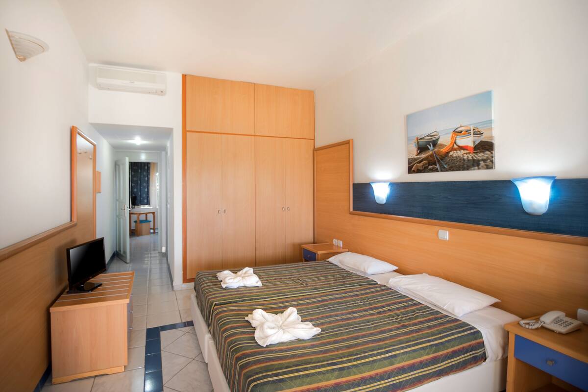 Une chambre d’hôtel équipée d’un lit, d’une télévision, d’un bureau et d’une armoire.