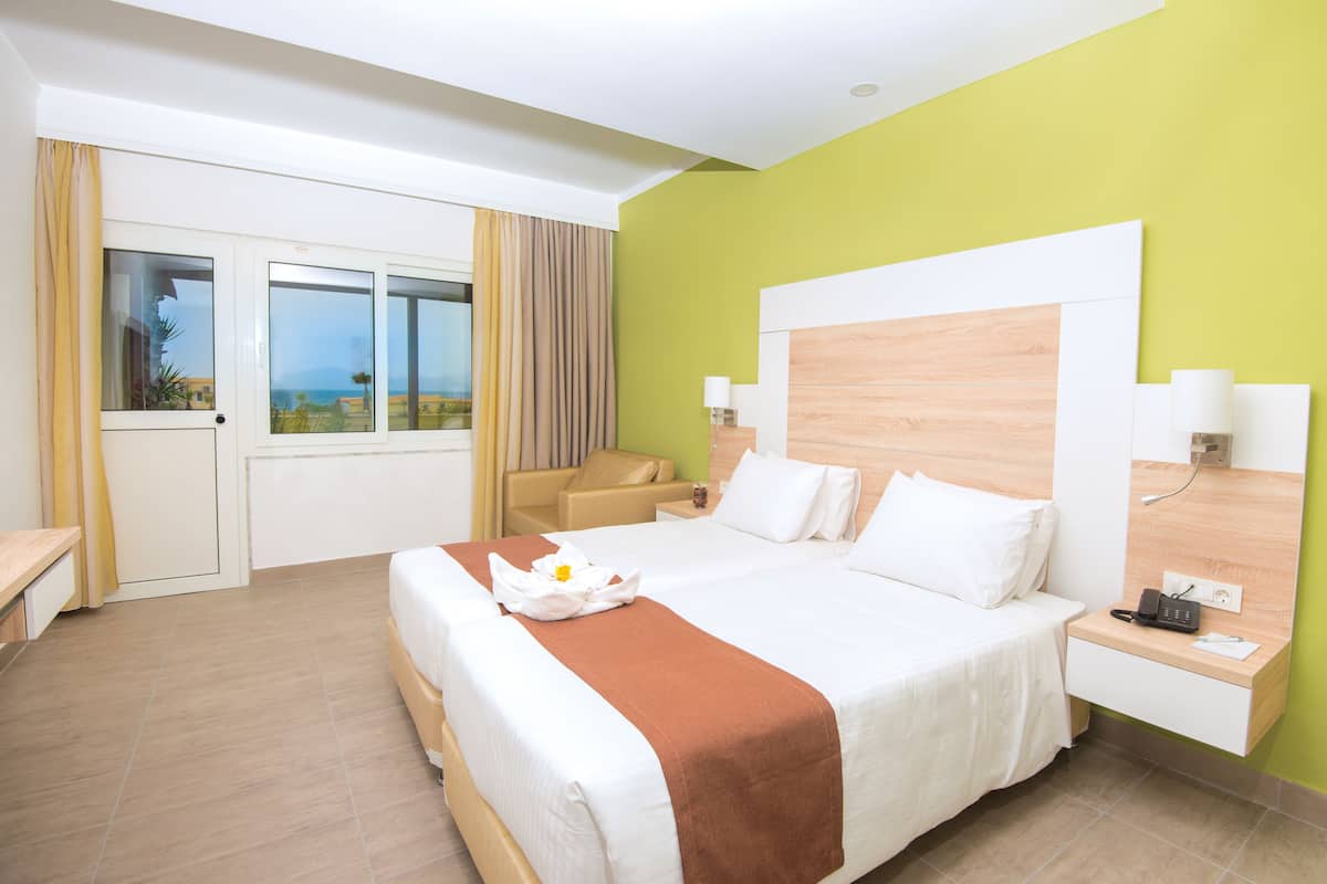 Une chambre d’hôtel avec un grand lit, un bureau, une chaise, une table de chevet et une vue sur l’extérieur.