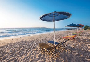 En la playa, sillas reclinables de playa, sombrillas, toallas de playa