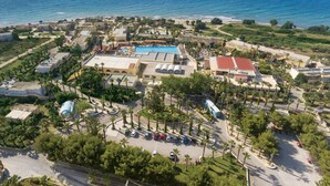 Vue aérienne d’un complexe hôtelier doté d’une piscine, d’un parking et d’un accès à la plage.