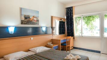 Ein Hotelzimmer mit Bett, Schreibtisch, Stuhl, Telefon und einem Fenster mit Vorhängen.