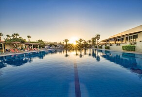 Una piscina al aire libre, sombrillas, sillones reclinables de piscina
